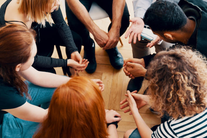 High angle on teenagers with alcohol addiction supporting each other during therapy